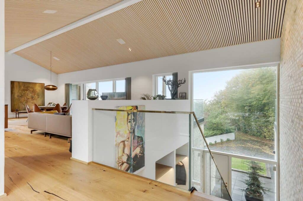 Overetage med glasværn og kig ned til stuen i Aarhus-villa.