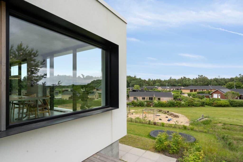 Hjørnefacade på hvid funkisvilla med store ruder.