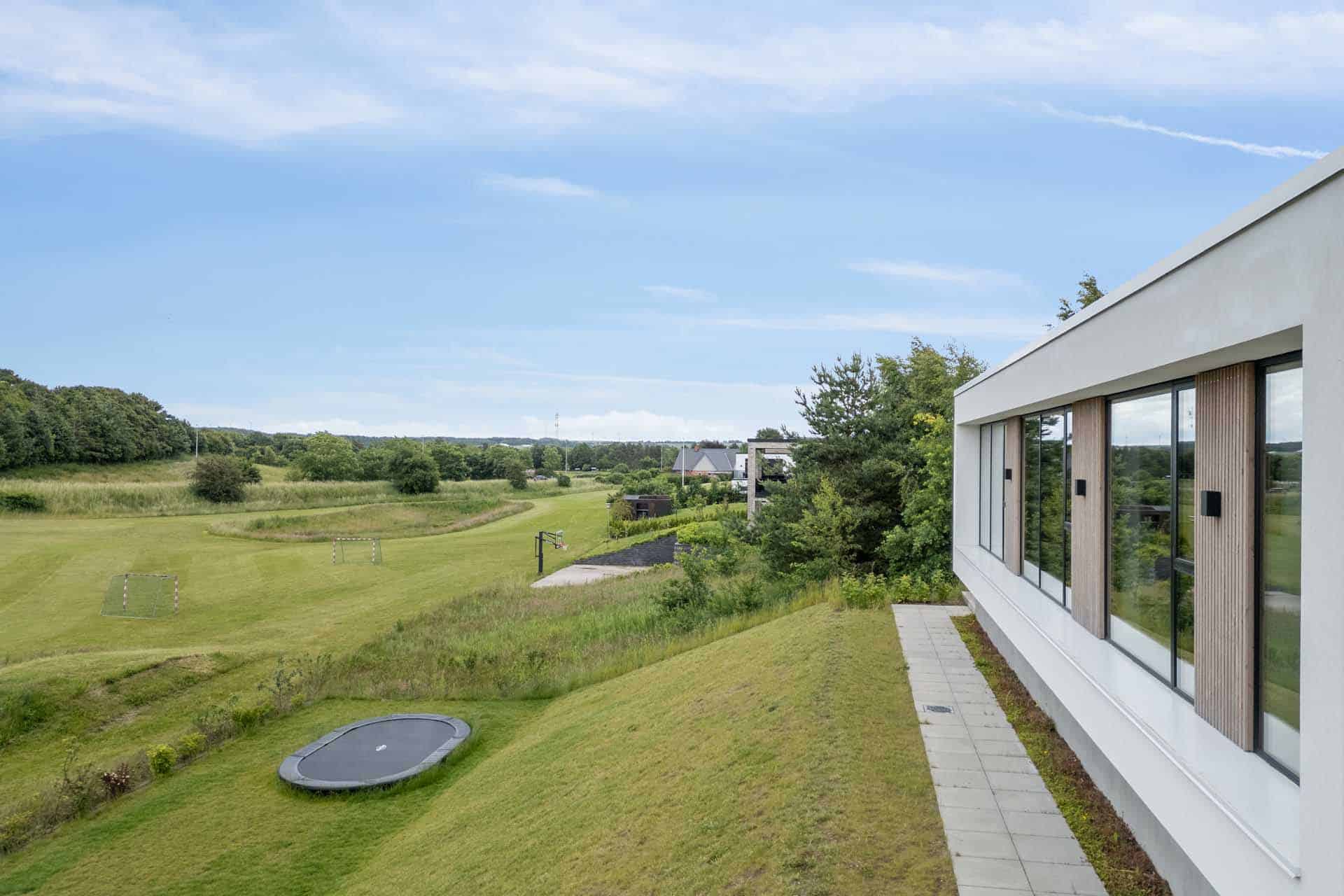 Langside af hvid villa med nyanlagt græsplæne.