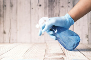 Gloved hand holding a spray bottle used to neutralize odors in a commercial facility