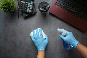 Cleaning a surface with gloves and a spray bottle as part of a commercial odor removal program
