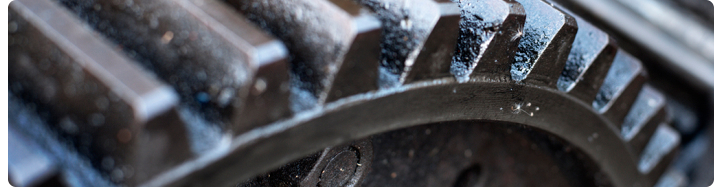 Close-up of industrial metal gear teeth with grease