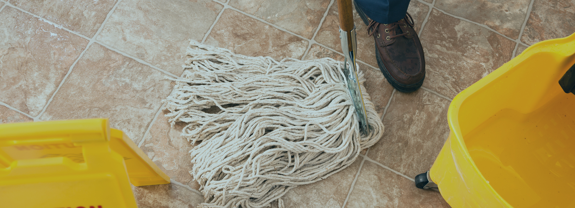 Janitor mopping tiled floor with caution sign
