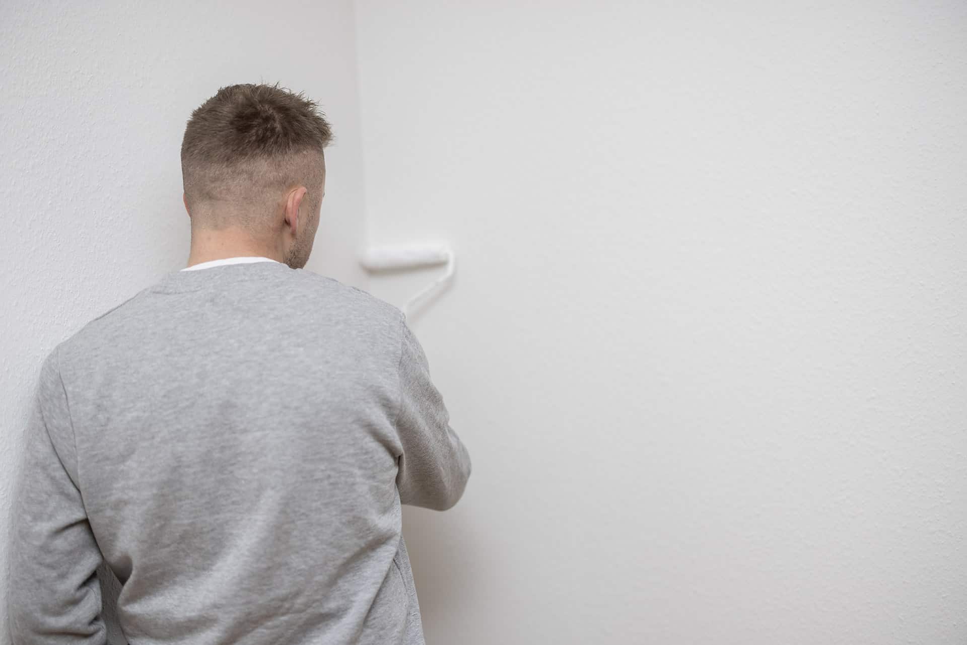 Professionel maler der ruller en hvid væg