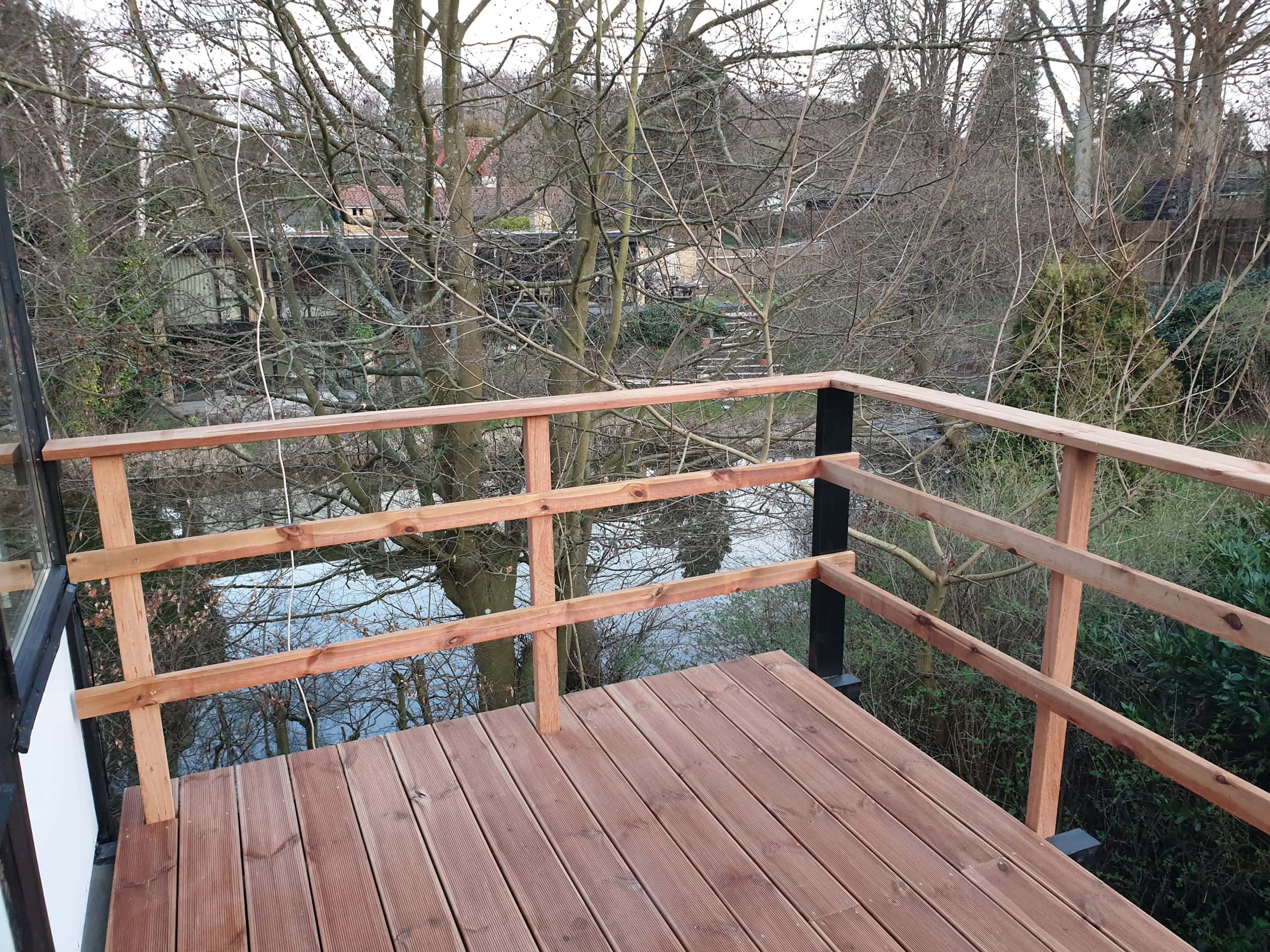 Træterrasse med flot mørkt hegn og udsigt til haven