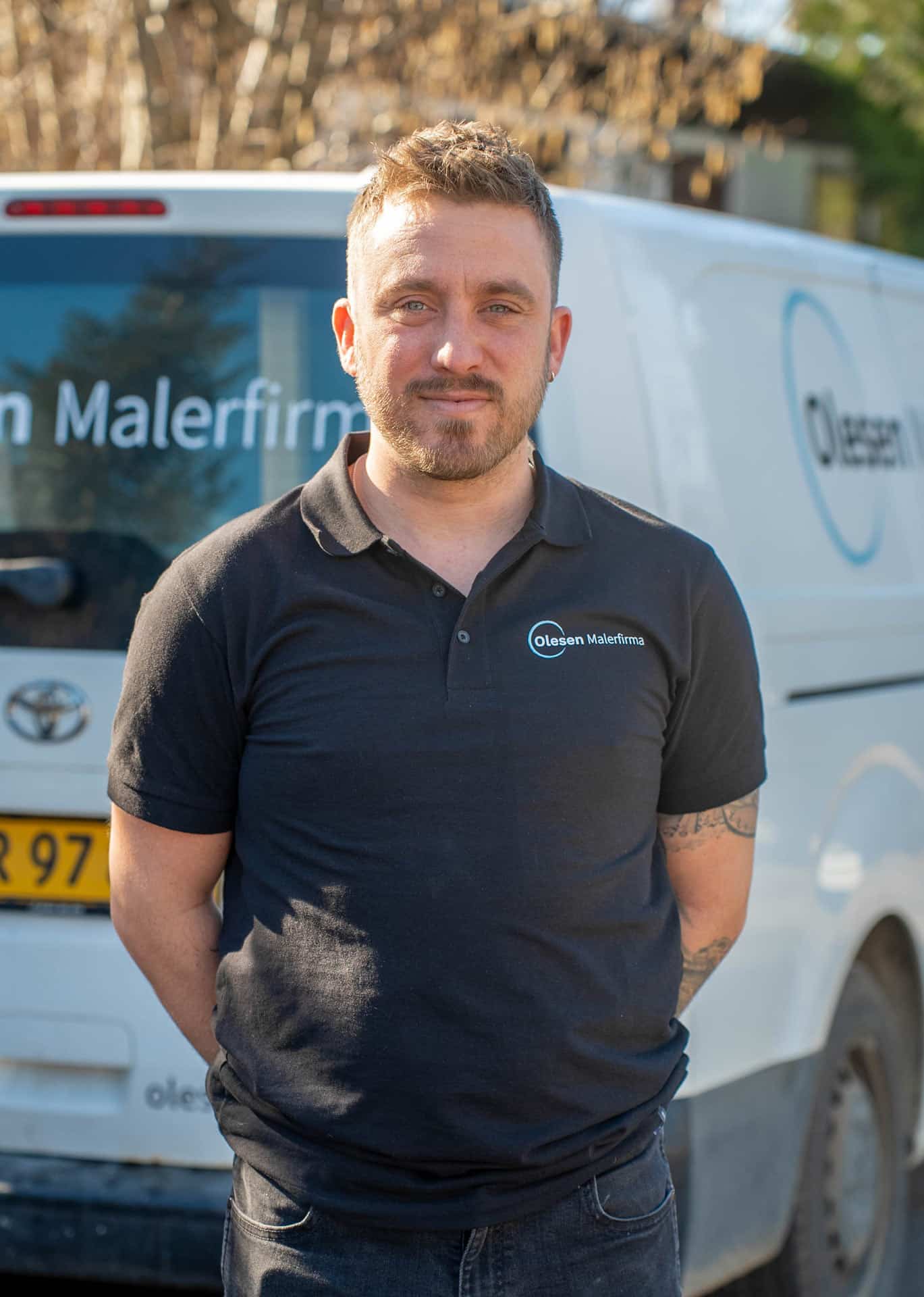 Smilende maler stående foran en hvid varevogn