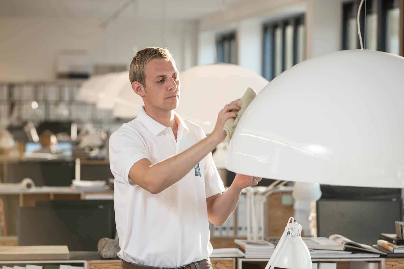Mand der støver en lampe af