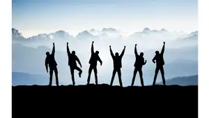 Celebrating teamwork and success with a group of people standing on a mountain peak at sunrise.