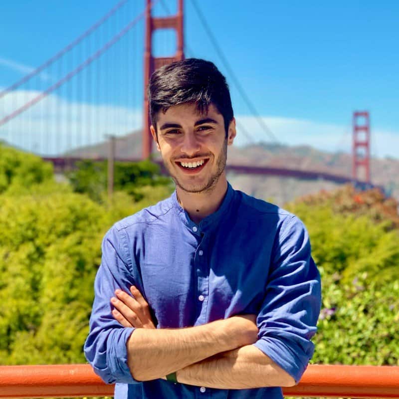 Smiling young man in blue shirt with Golden Gate Bridge background.