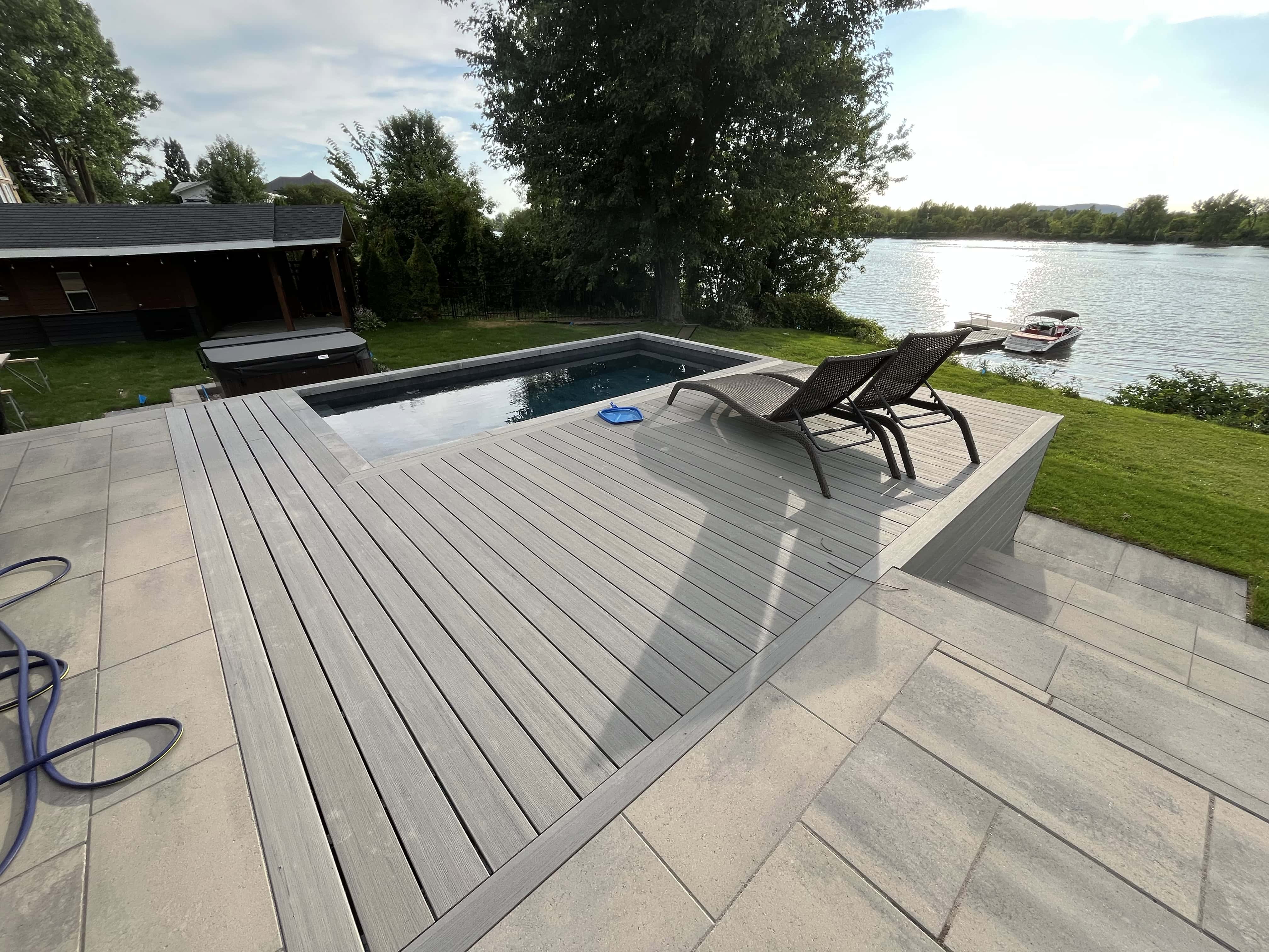 Large wooden deck wrapped around a bayto plunge swimming pool in cottage setting on a lake