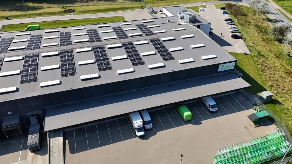 Stort solcelleanlæg på tag af lagerbygning i solrigt vejr.