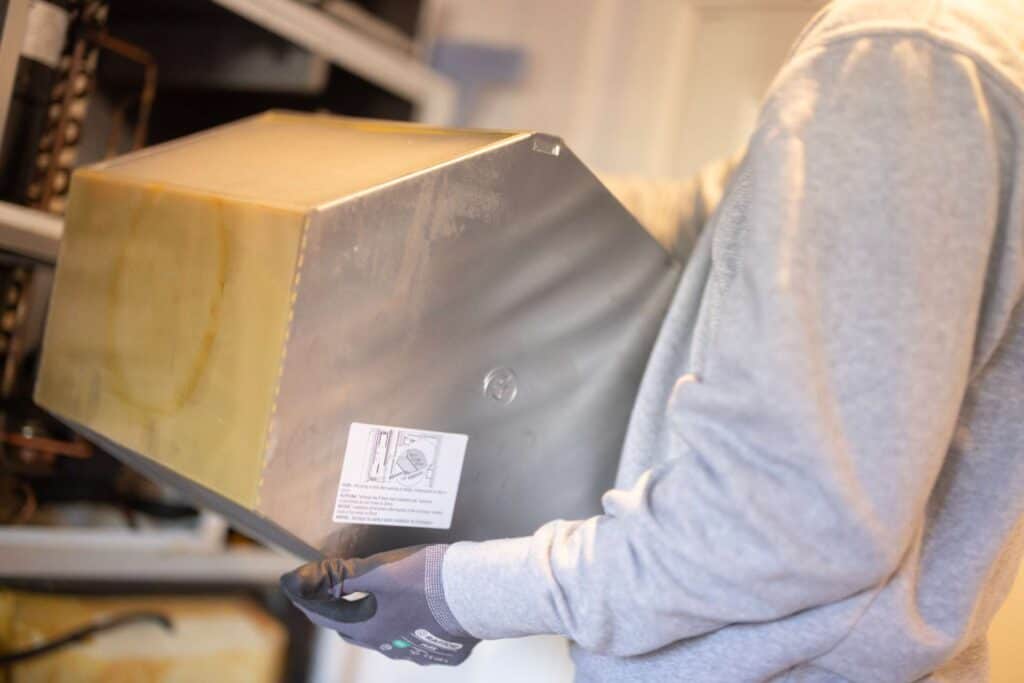 Medarbejder løfter metalkasse