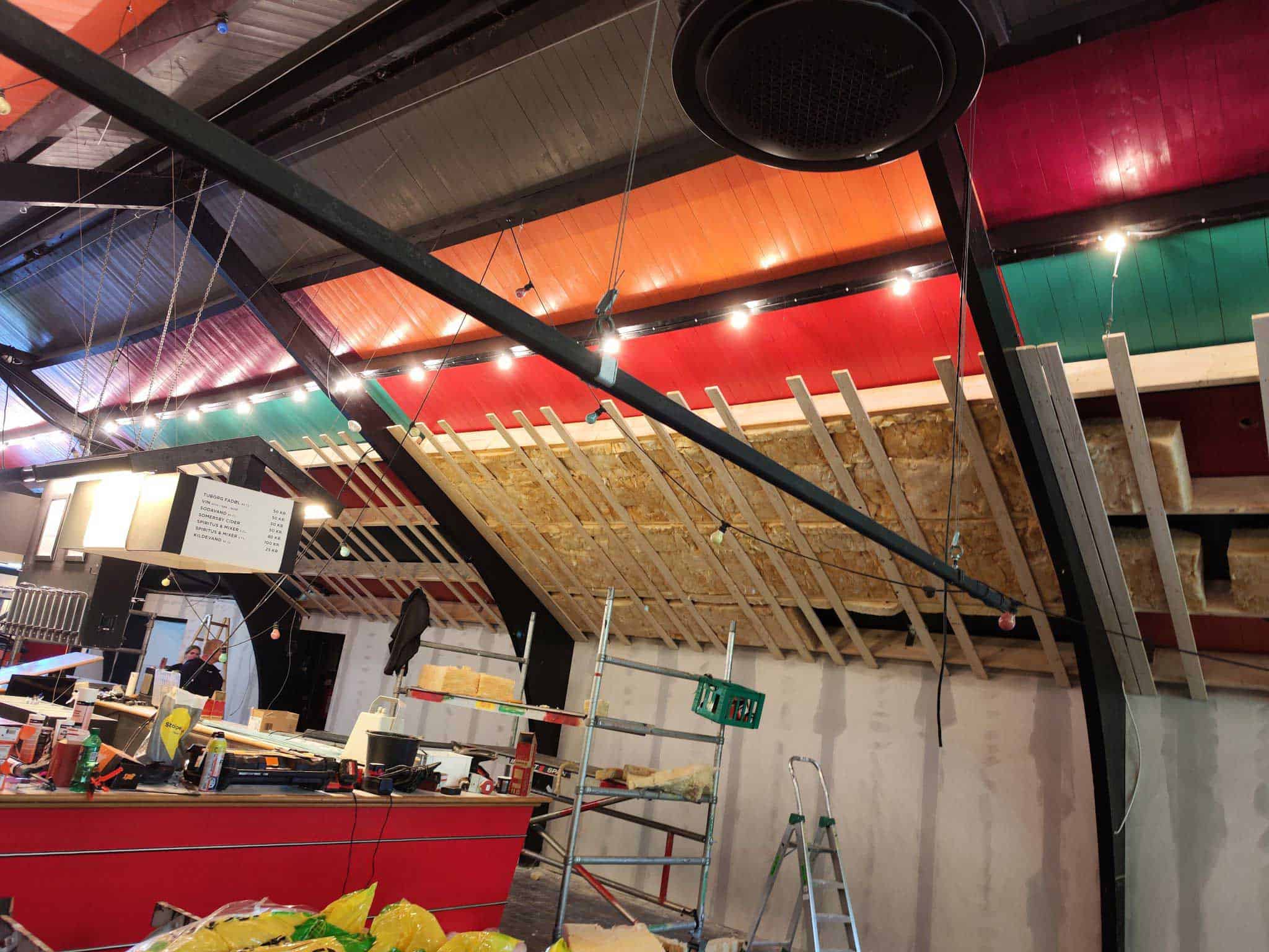 Farverigt loft og malede bjælker i erhvervslokale under renovering udført af maler.