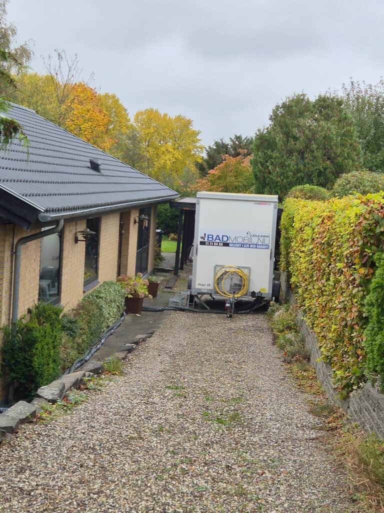 Toiletvogn leje i en privat grusindkørsel ved gavl.