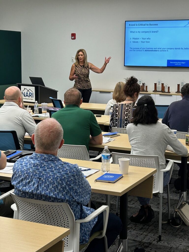 Diane Welhouse presents a powerpoint presentation, speaking to a peer advisory group in a meeting room.