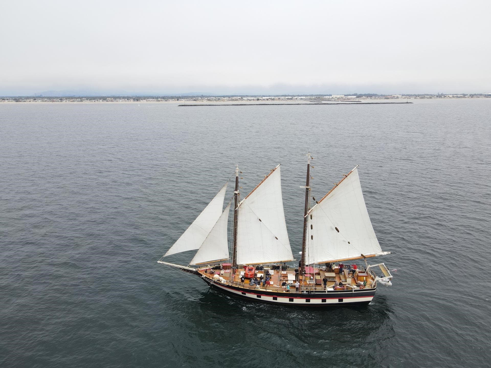 Sailing boat with white sails on calm waters at Channel Islands Harbor.
