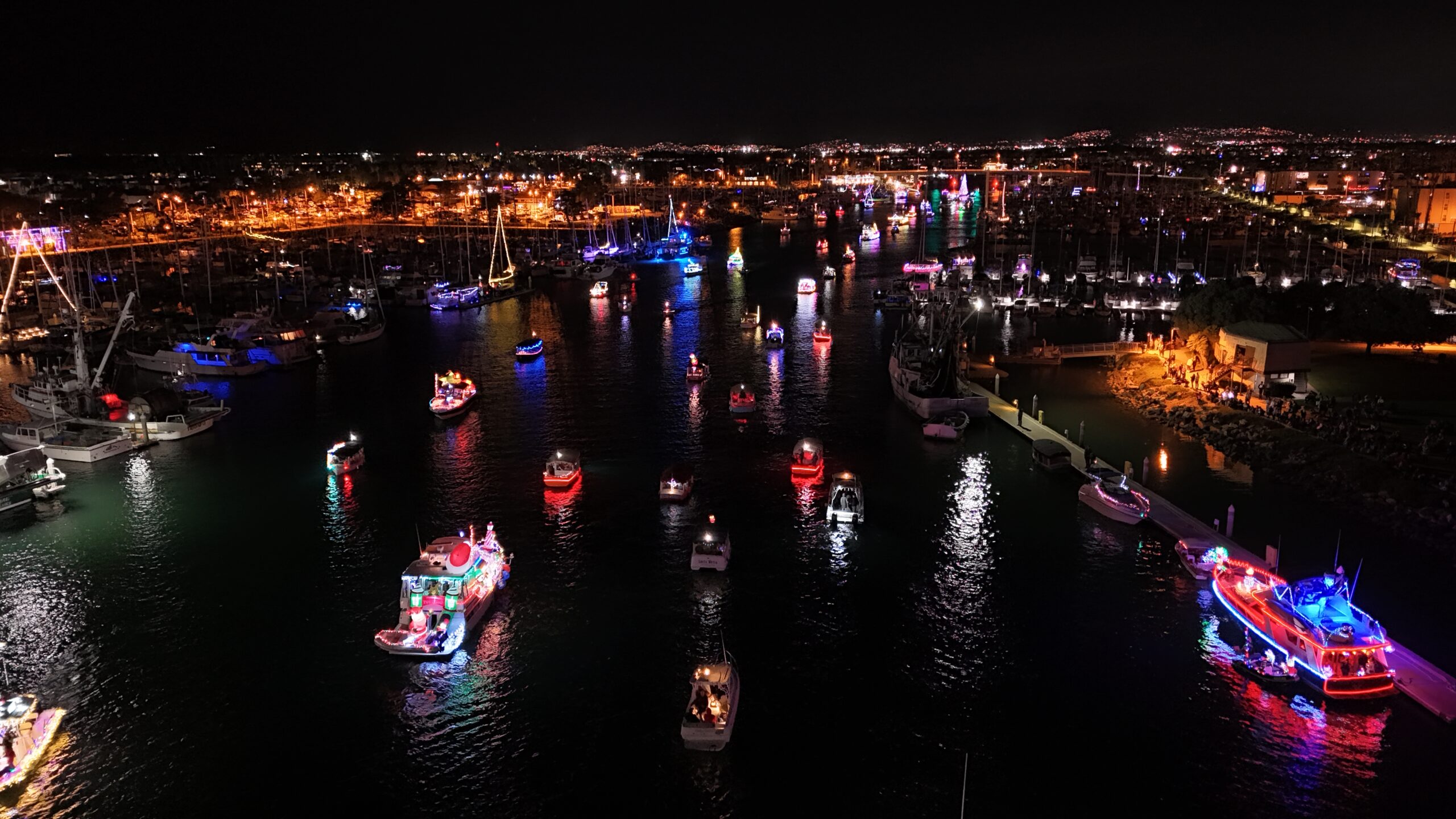 Night scene of Channel Islands Harbor with colorful boats lit up for the Parade of Lights.