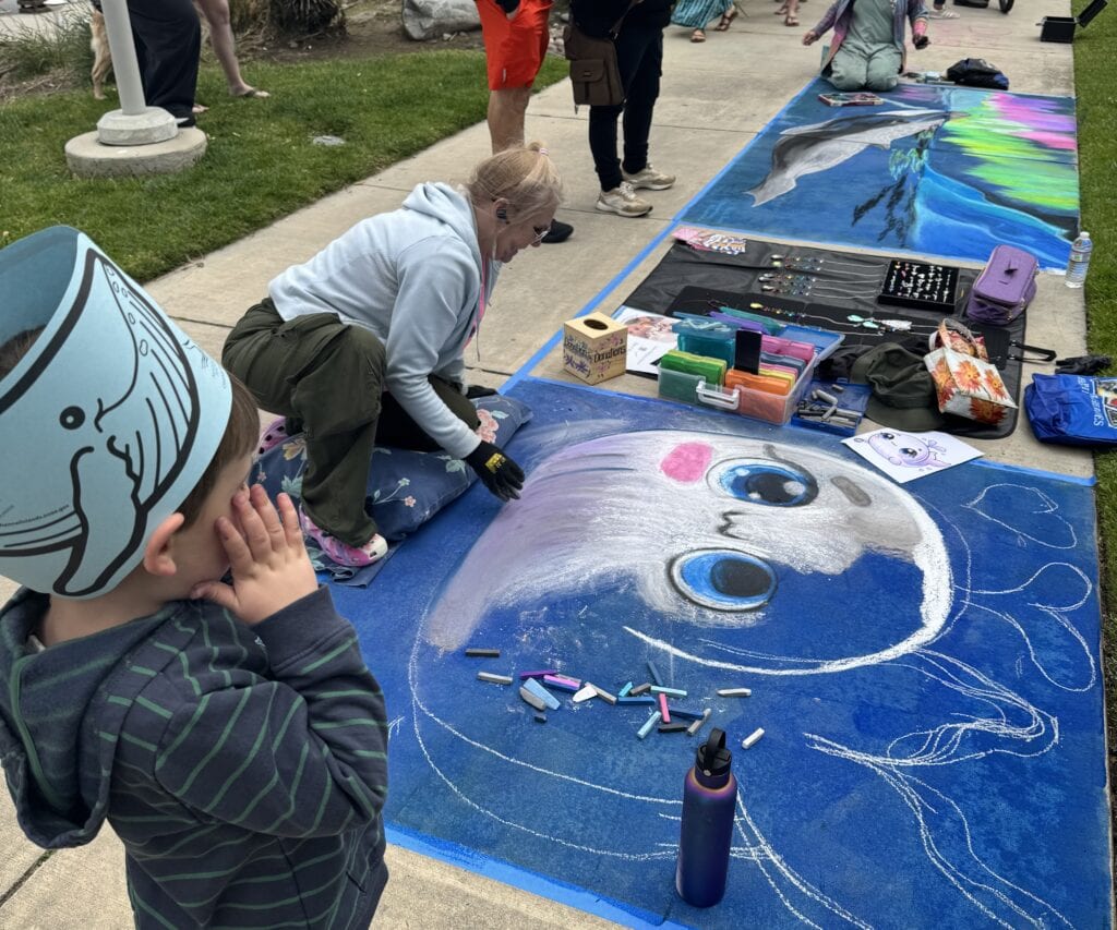 Artist creating large chalk mural at Channel Islands Harbor event.