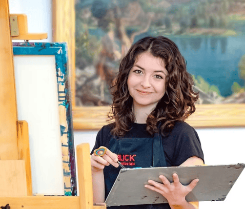 Young woman painting outdoors at Channel Islands Harbor with scenic water view.