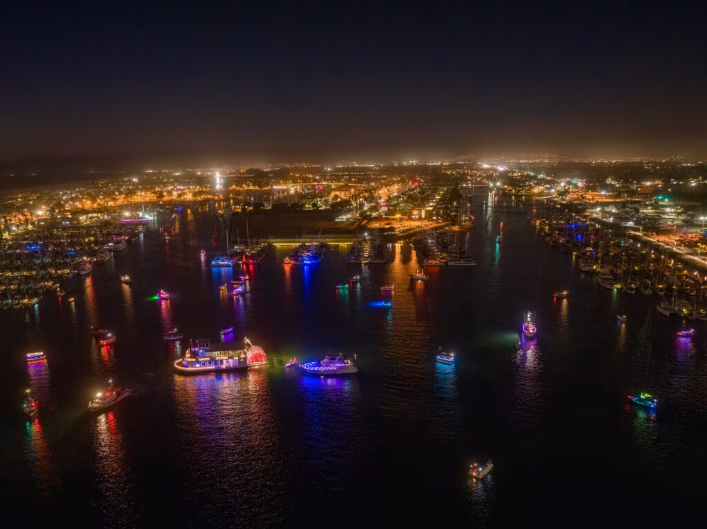 Night view of Channel Islands Harbor with colorful boat lights reflecting on water.