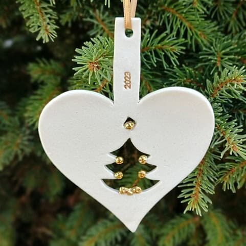 Julehjerte ornament med grantræ, lavet af keramik, hænger på juletræet.