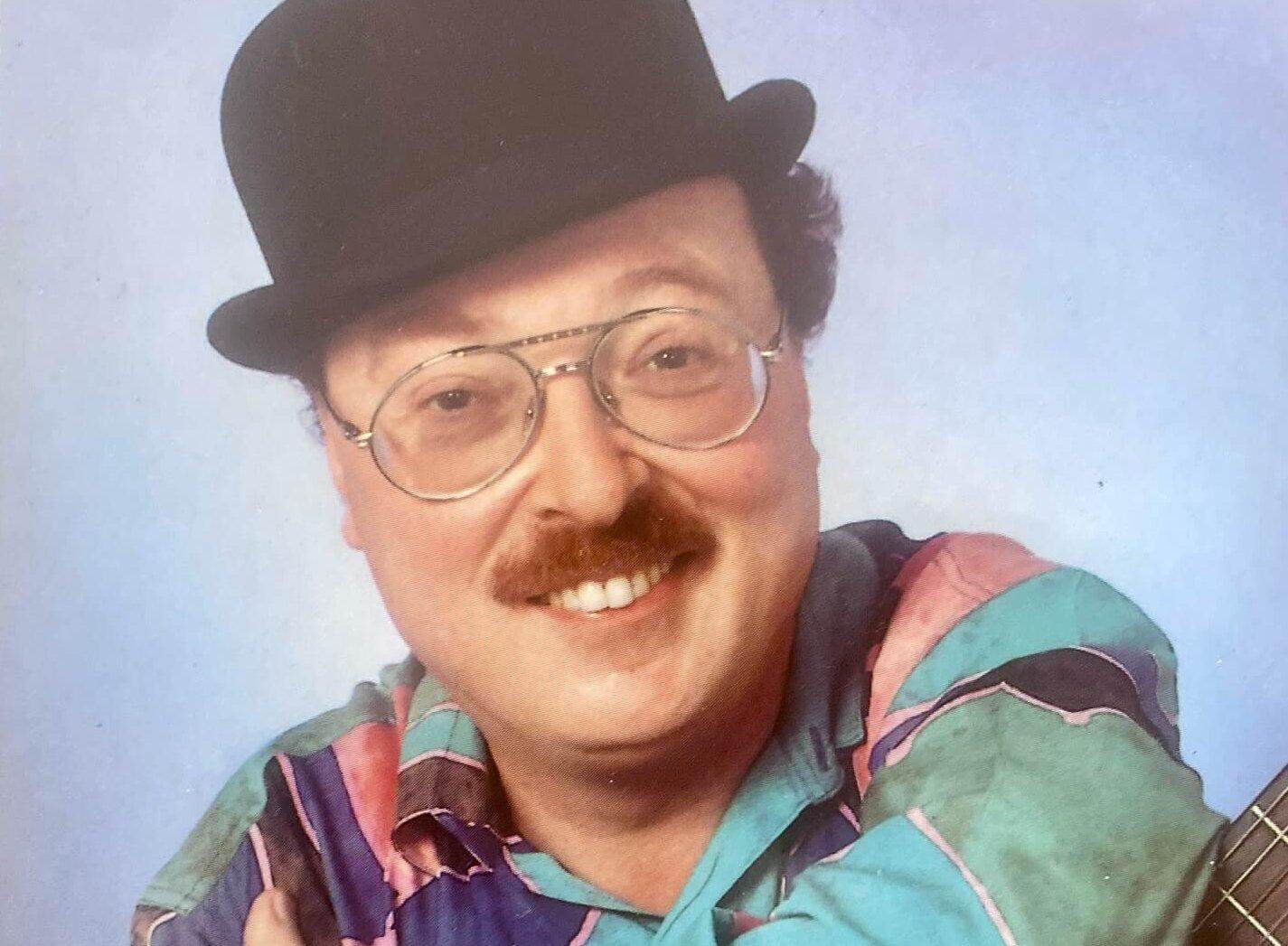 Wicky Junggeburth mit Melone, Brille und Gitarre