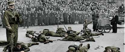 Historische Aufnahme von als Soldaten verkleideten Karnevalisten, die während des Rosenmontagszugs am Boden robben