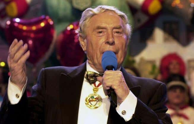 Ludwig Sebus im Frack mit Ehrenkette singt ins Mikrofon
