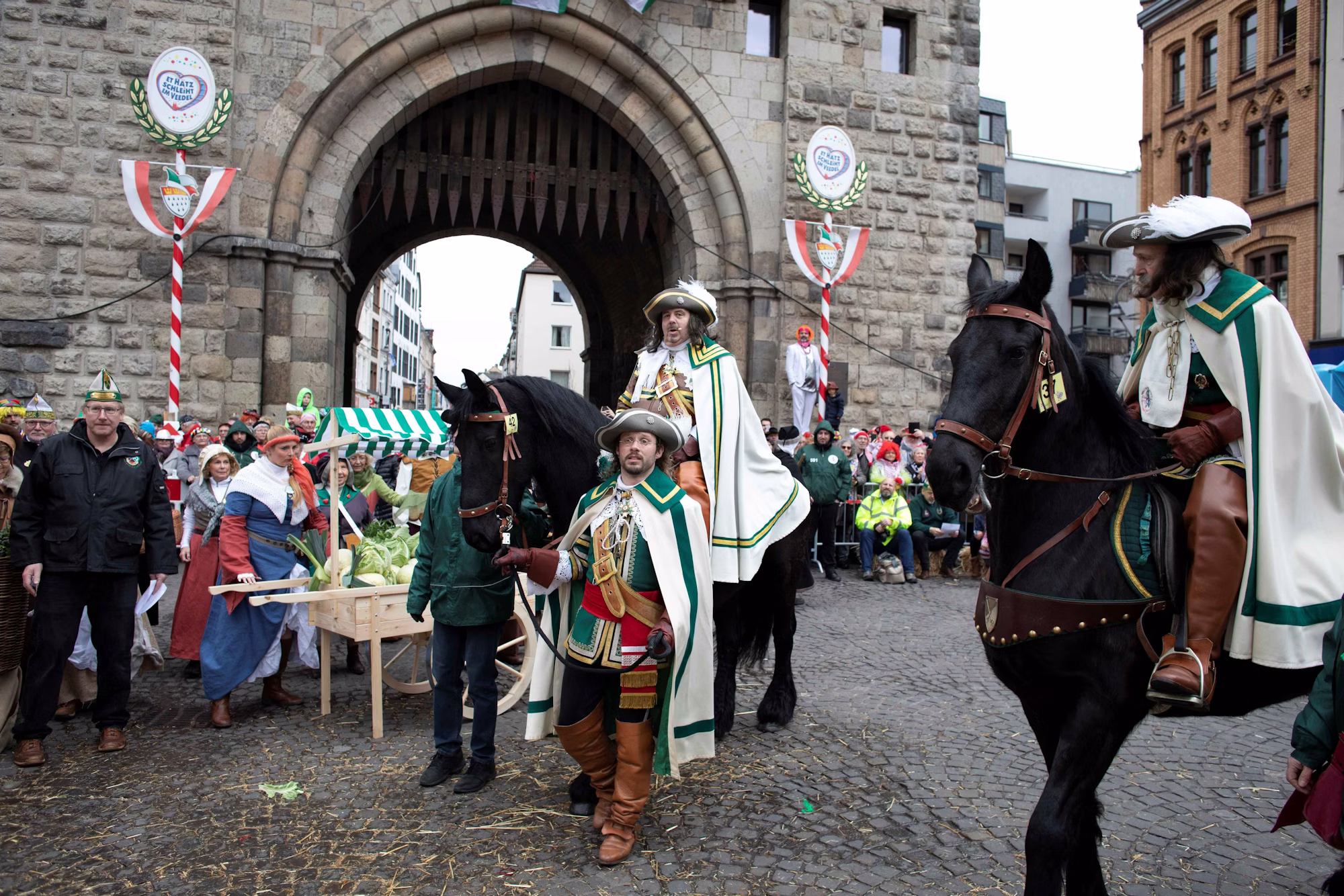 Reiter in grün-weißen Uniformen zu Pferd bei einem Kölner Karnevalsumzug am Stadttor