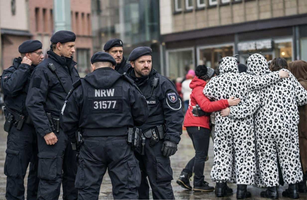 Polizisten der NRW-Bereitschaftspolizei neben Feiernden in Tierkostümen bei Weiberfastnacht