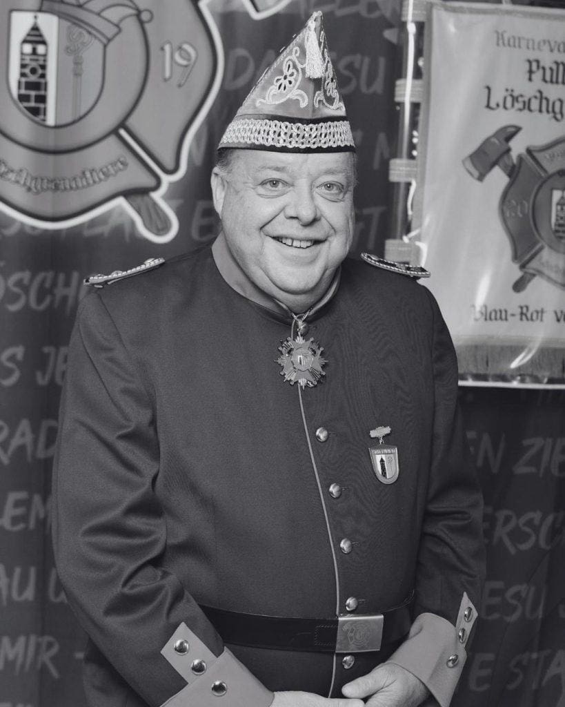 Mann in Karnevalskostüm mit Narrenkappe bei Kölner Karneval.