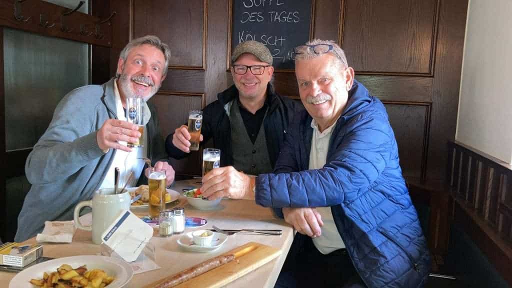 Drei Männer beim Karnevalstreffen in Köln, feiern und stoßen an.