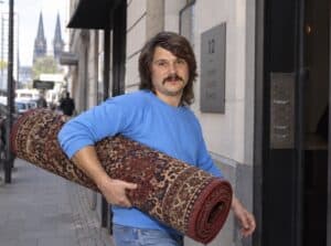 Tommy Engel trägt einen Teppich unter dem Arm und geht zum Vorsingen