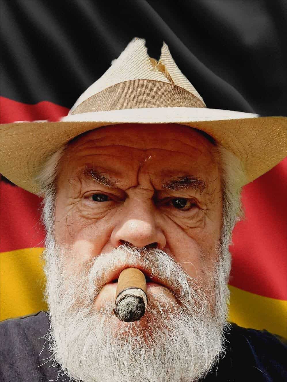 Mann mit Zigarre und Hut vor einer Deutschlandfahne
