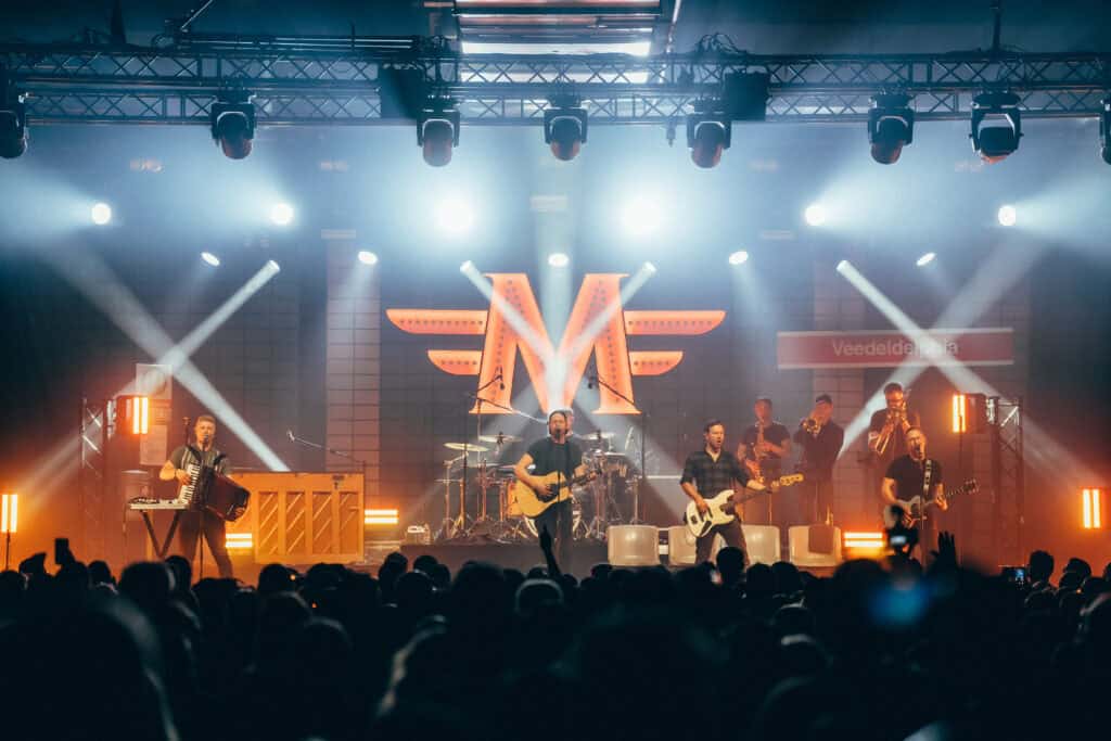 Band Miljö live auf der Bühne mit großem Vereinslogo im Hintergrund