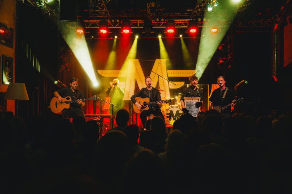 Band Miljö bei einem Konzert in einem kleinen Veranstaltungsraum mit roter Bühnenbeleuchtung