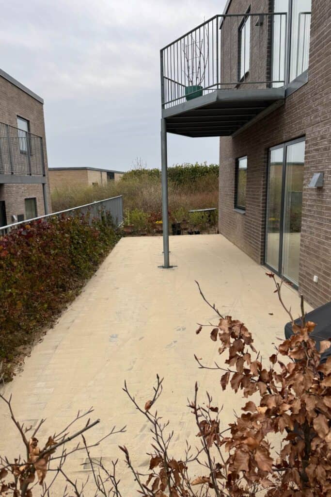 Nyanlagt stenterrasse med sand på foran et hus