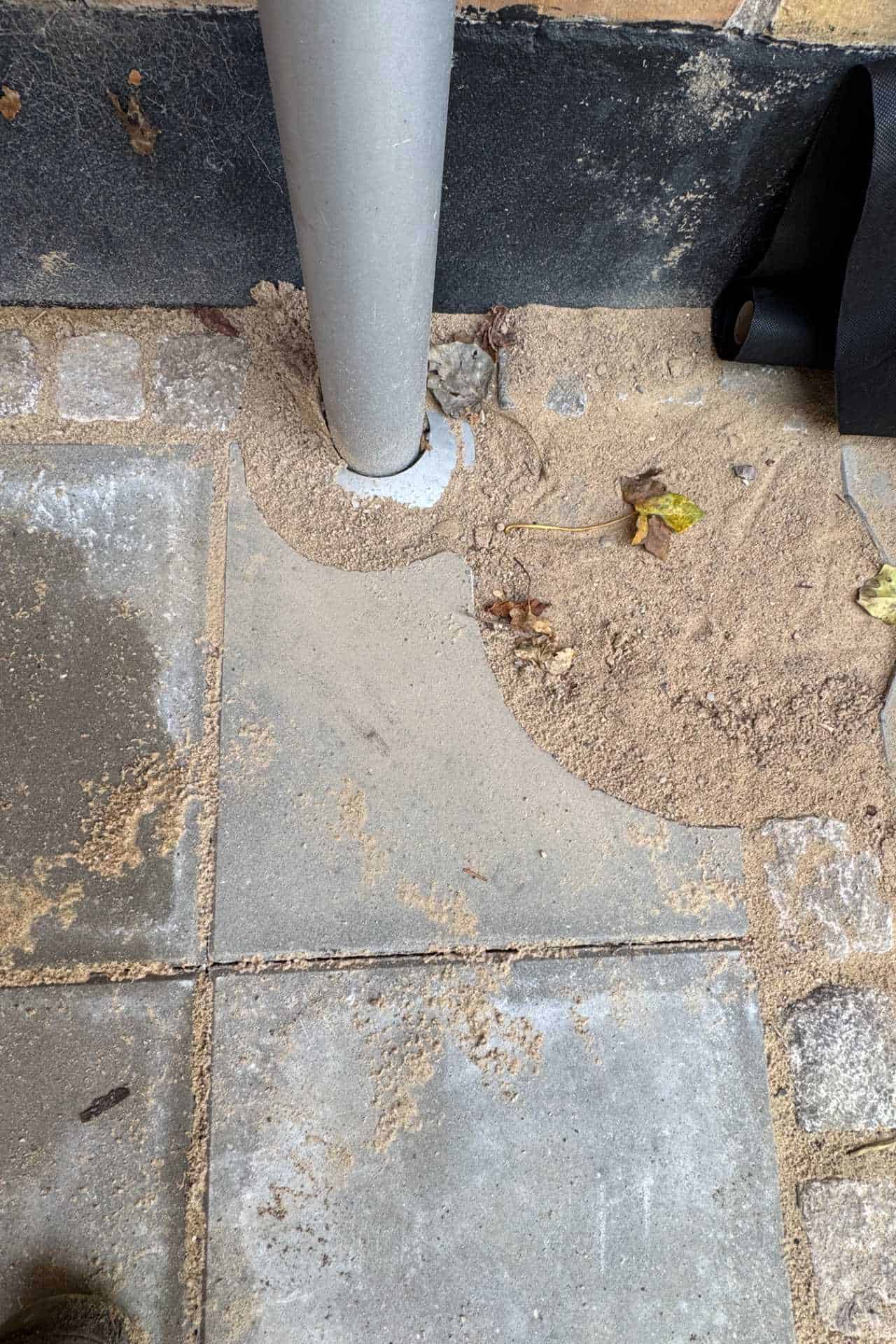 Nærbillede af flisebelægning omkring stolpe med fugesand, udført af entreprenør