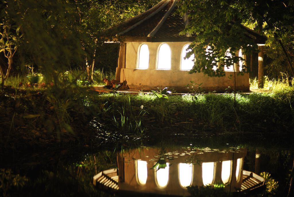 Serene eco village scene with a small house and pond at Wongsanit Ashram.