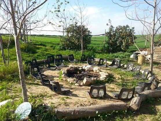 Community fire circle with chairs in a natural eco village setting.
