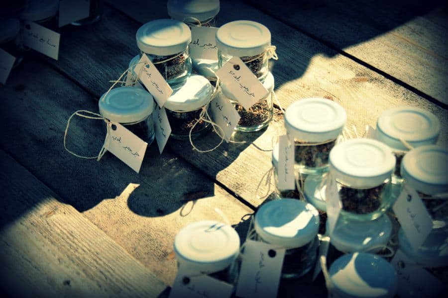 Small glass jars with labels on a wooden surface at the Global Ecovillage Network event.