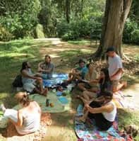 People sitting in a circle outdoors at a community event in a green park.