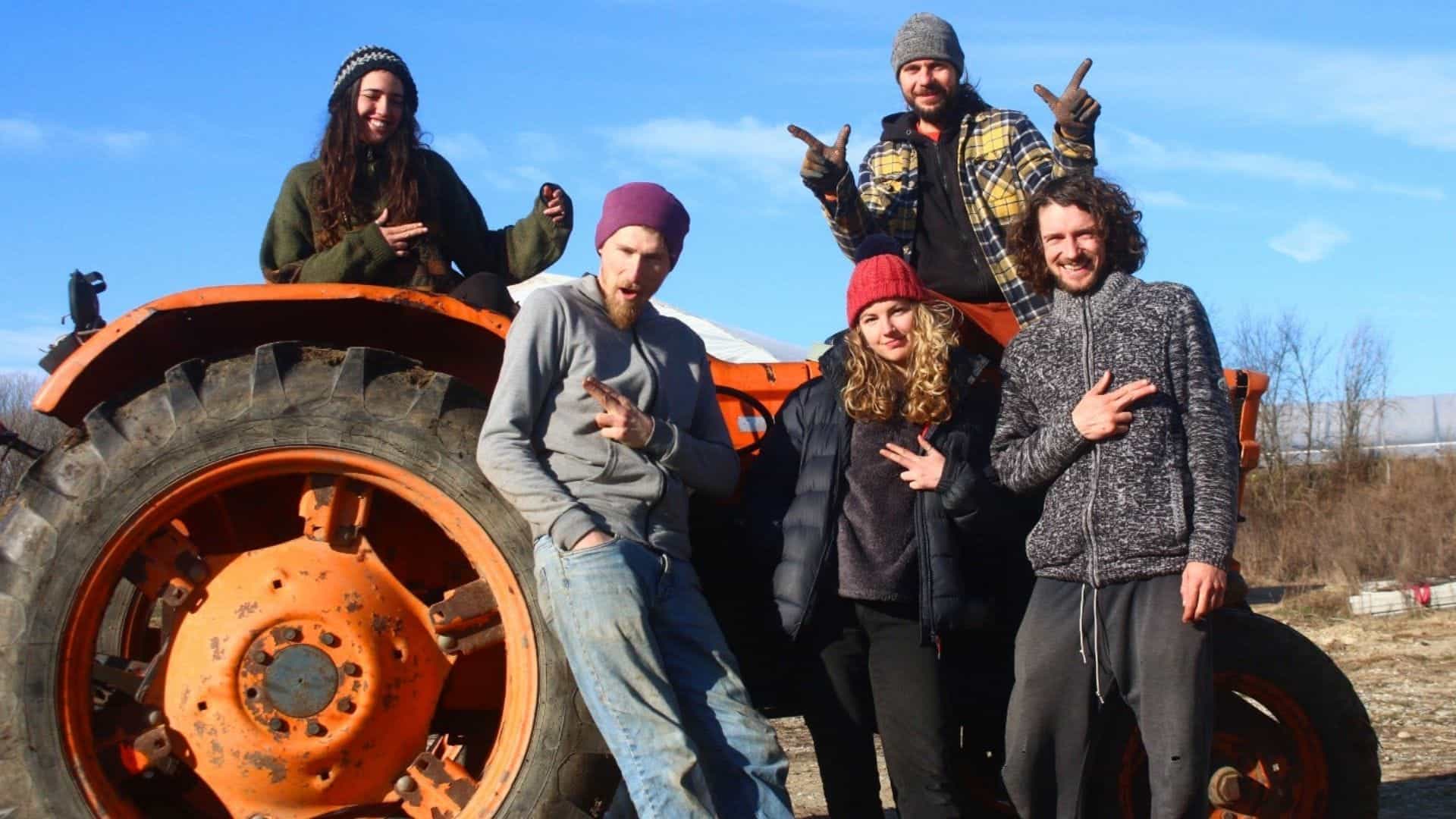 Group of diverse people with tractor in outdoor eco-village setting.