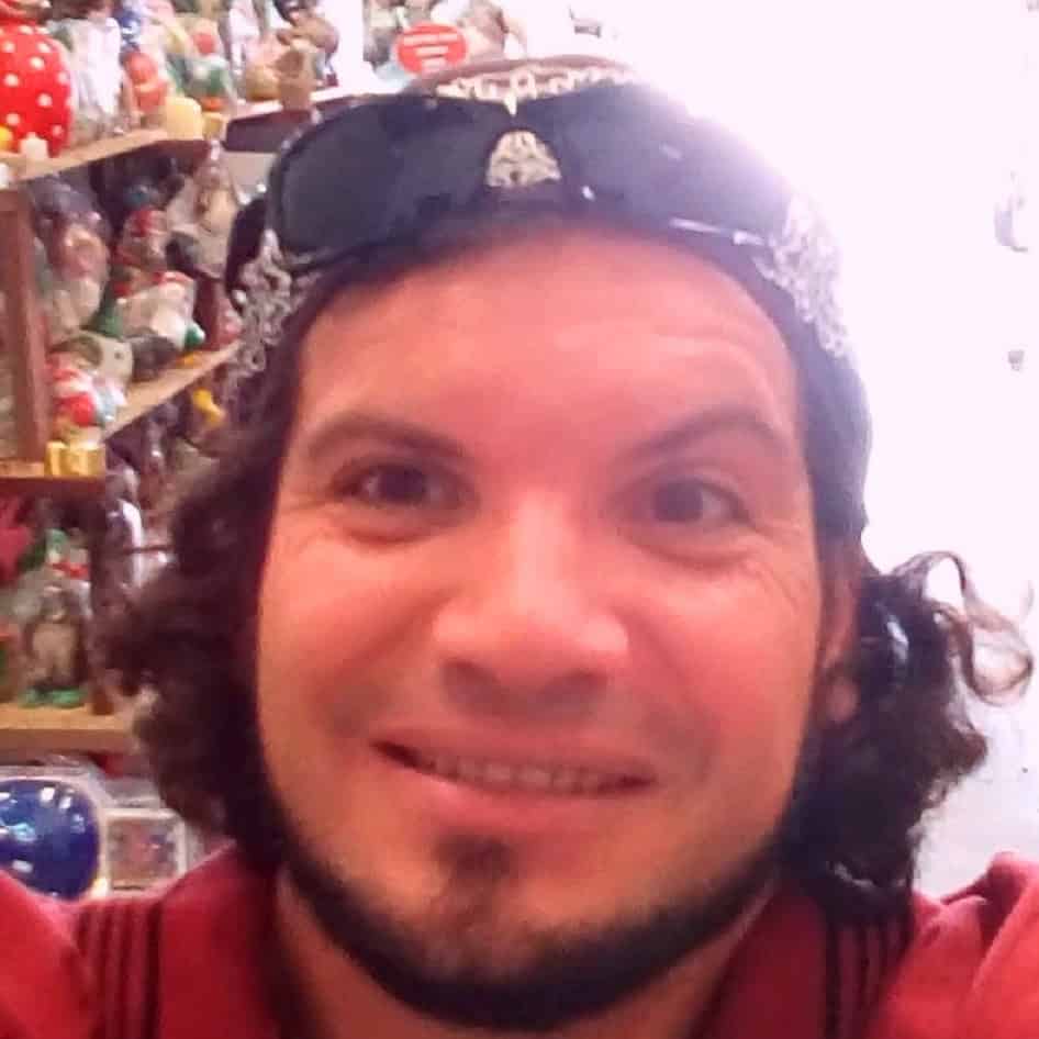 Close-up of a smiling man with curly hair and sunglasses on his head.