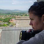 Female photographer capturing scenic view from rooftop in a rural village setting.