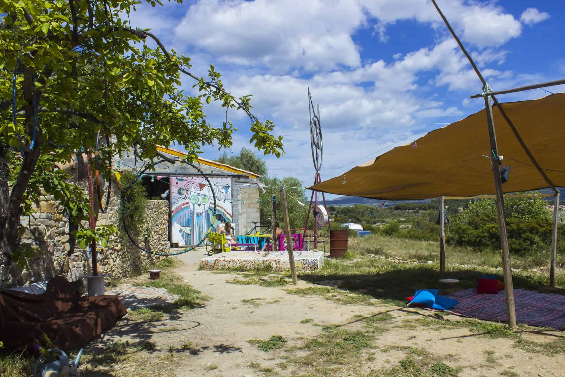 Ecovillage community area with tents, murals, and natural surroundings.