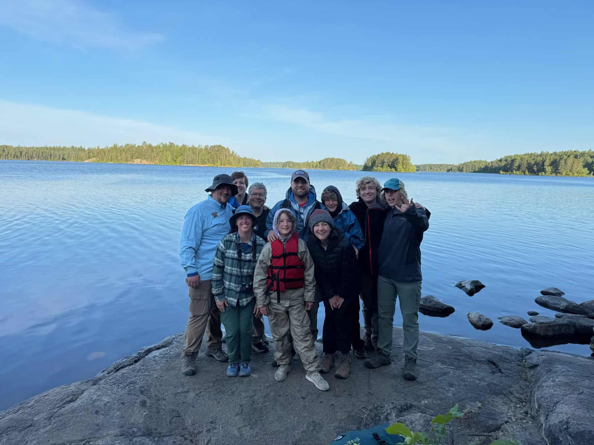 Group of people at a lakeside, representing eco-community collaboration.