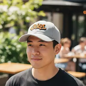 Man wearing GABA branded grey cap outdoors, casual style.