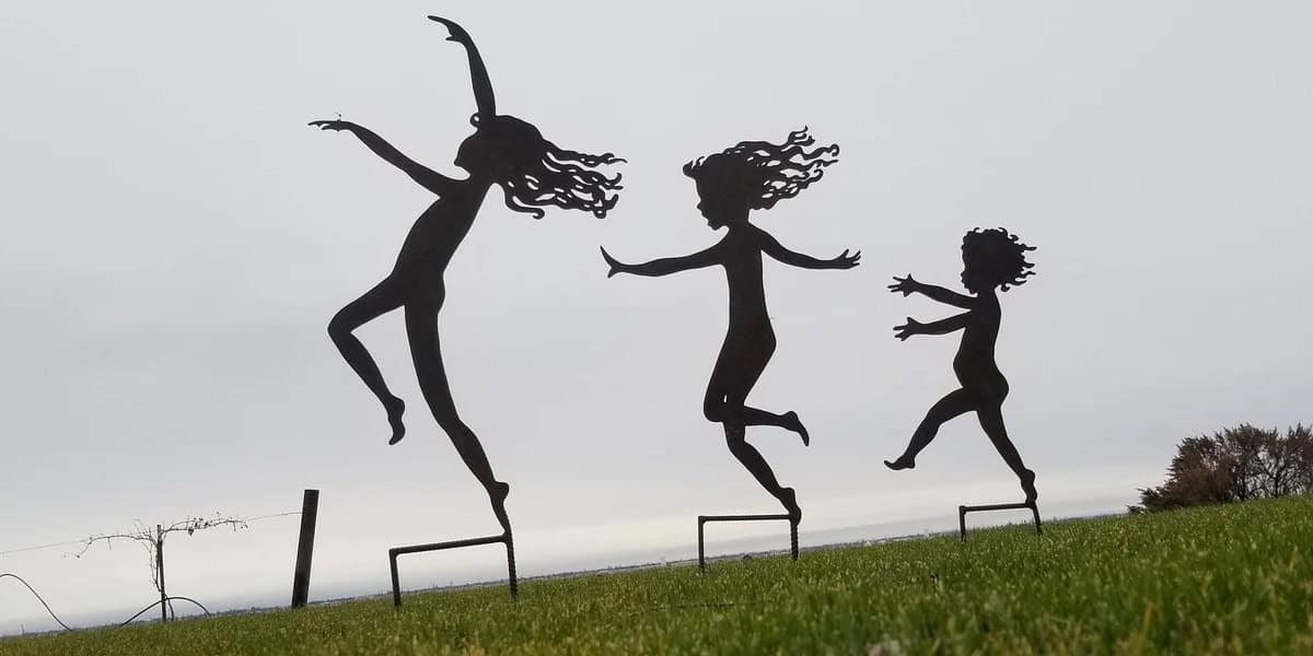 silhouette garden stakes of three dancing sisters