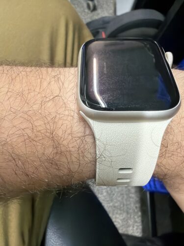 שעון חכם עם מסך מגע על פרק היד של אדם, עם רצועת גומי לבנה, במשרד או בבית.